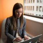 Photo of Woman Sitting on Chair and Typing on Silver Macbook